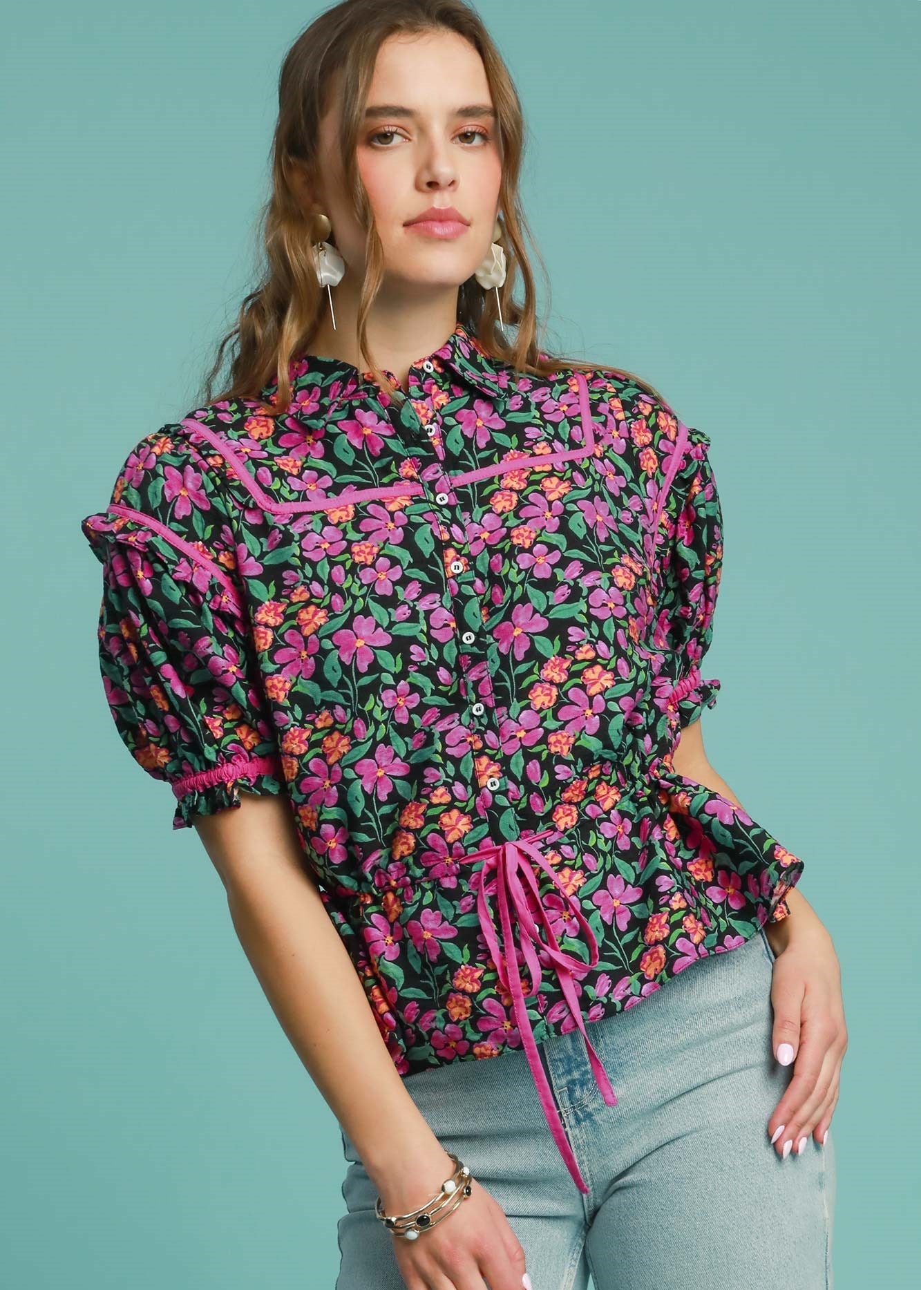 Woman wearing a floral blouse with puff sleeves against a teal background